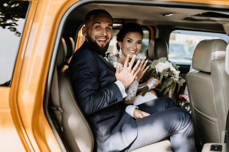 Lächelnd Hochzeitspaar im Auto zeigt die Eheringe.